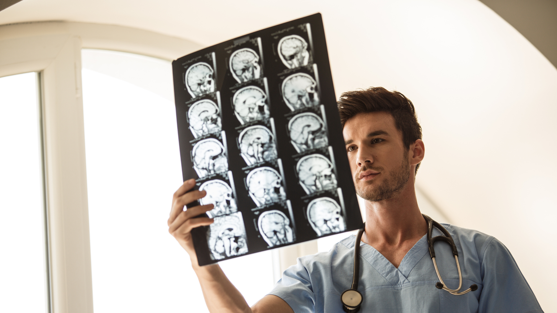 Profesional de la salud observando una resonancia magnética cerebral en un entorno clínico.
