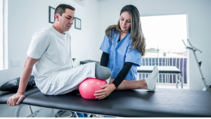 Hombre con amputación mayor en pierna derecha realizando ejercicios de rehabilitación con una fisioterapeuta en una clínica.