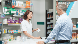 Farmacéutica atiende a un paciente en una farmacia, entregando un medicamento como parte de la atención en salud.