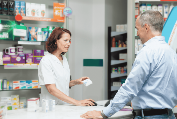 Farmacéutica atiende a un paciente en una farmacia, entregando un medicamento como parte de la atención en salud.