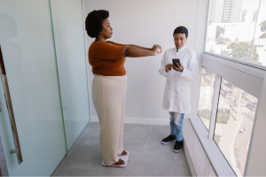 Mujer midiendo su composición corporal con una bascula por la bioimpedancia. Medico que revisa los datos.
