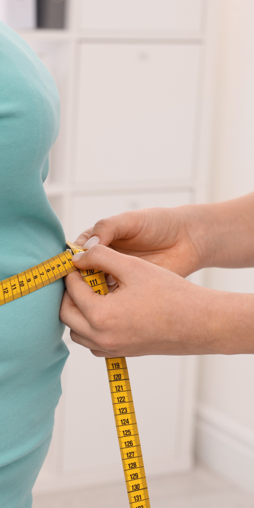 Profesional de la salud midiendo la cintura de una persona con obesidad y sobrepeso con una cinta métrica.