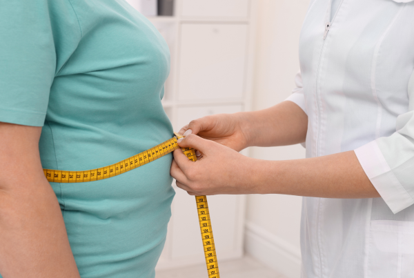 Profesional de la salud midiendo la cintura de una persona con obesidad y sobrepeso con una cinta métrica.