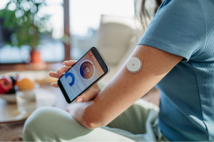 Mujer midiendo la diabetes con nuevas tecnología tipo mobil y el botón tipo flash de monitorización.