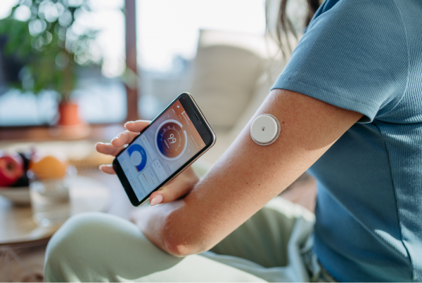 Mujer midiendo la diabetes con nuevas tecnología tipo mobil y el botón tipo flash de monitorización.