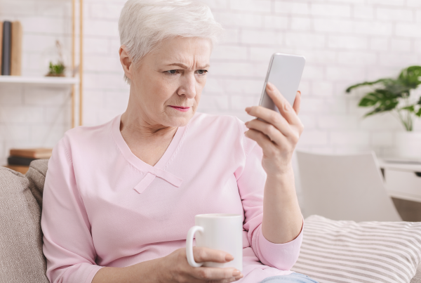 Persona adulta con dificultad para ver con claridad la pantalla del móvil, representando síntomas del edema macular diabético en personas con diabetes