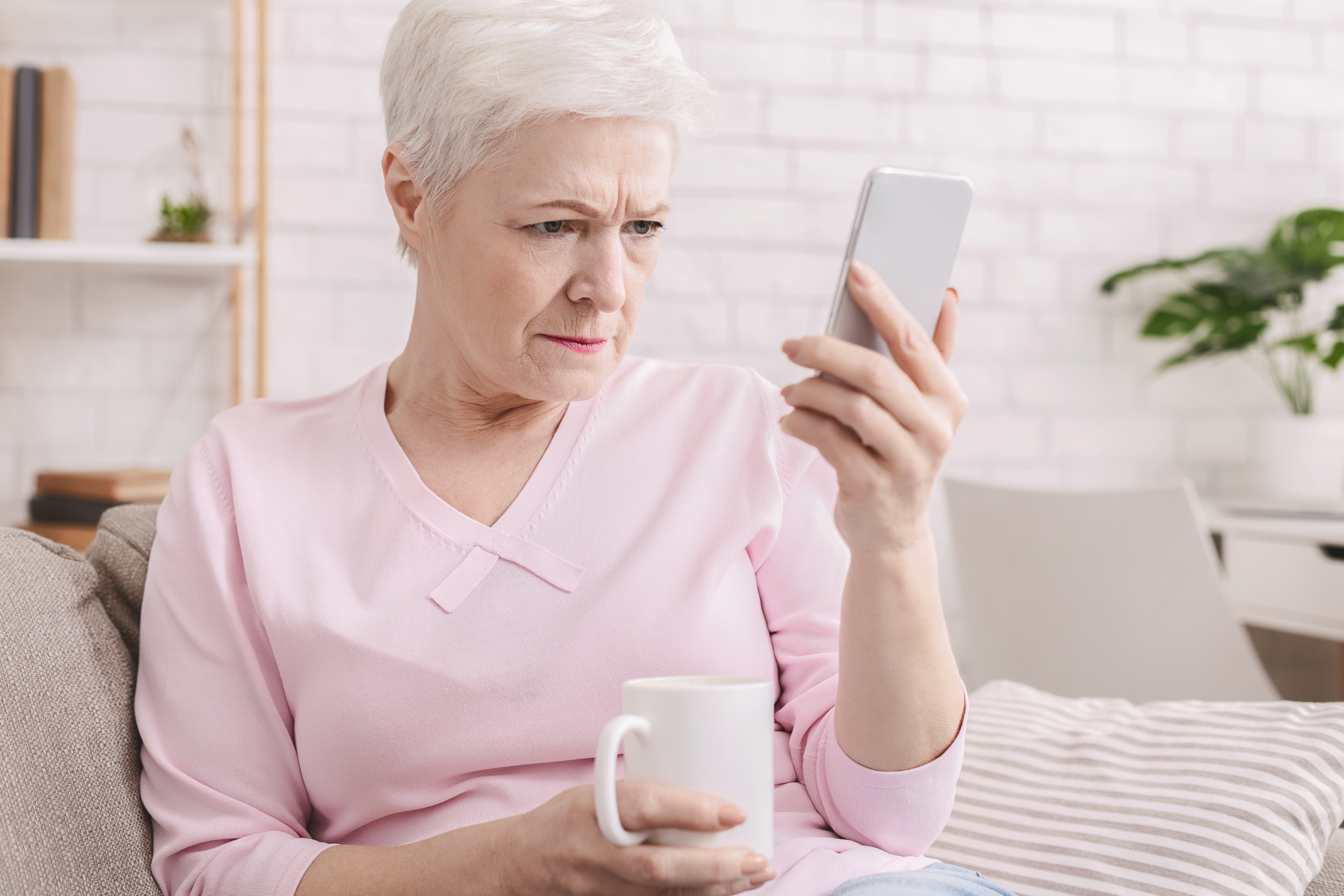 Persona adulta con dificultad para ver con claridad la pantalla del móvil, representando síntomas del edema macular diabético en personas con diabetes